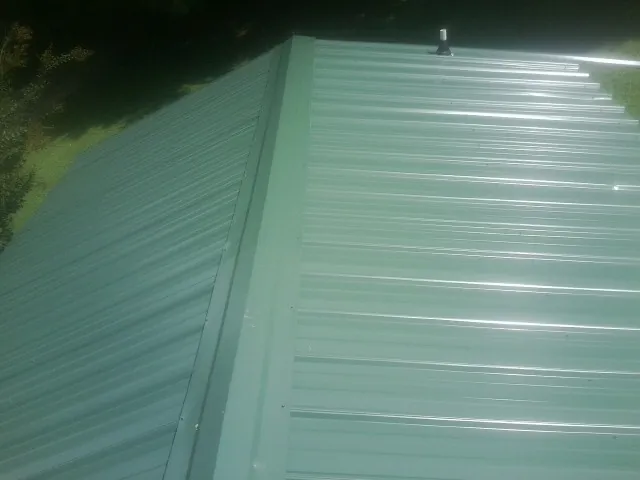 New green metal panels meeting at the ridge of a roof — Flat Roof Repair work by our crew in Markham